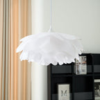Close view of the overlapping white petals of this Clérachic pendant, unlit, beside a dark shelf and peach curtains.