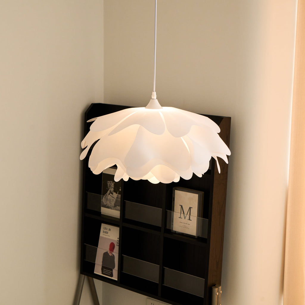 Another angle of a Clérachic petal pendant in a corner, its curved white layers casting a warm glow beside a dark display shelf.