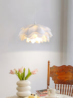 A Clérachic petal pendant above a dining table with pink tulips in a vase and a carved wooden chair, against a pale grey wall.