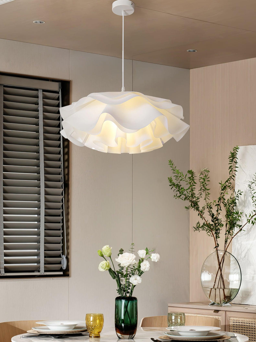 A Clérachic pendant with a frilly lower tier, above a set dining table with white flowers and a dark green vase.