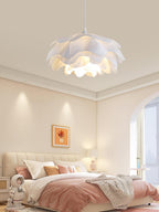 Tall view of a Clérachic petal pendant over a pink-and-cream bedroom with a tufted headboard and a throw blanket.