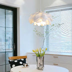 A Clérachic pendant with ruffled white petals in a bright room with louvred blinds and tulips in a silver vase.