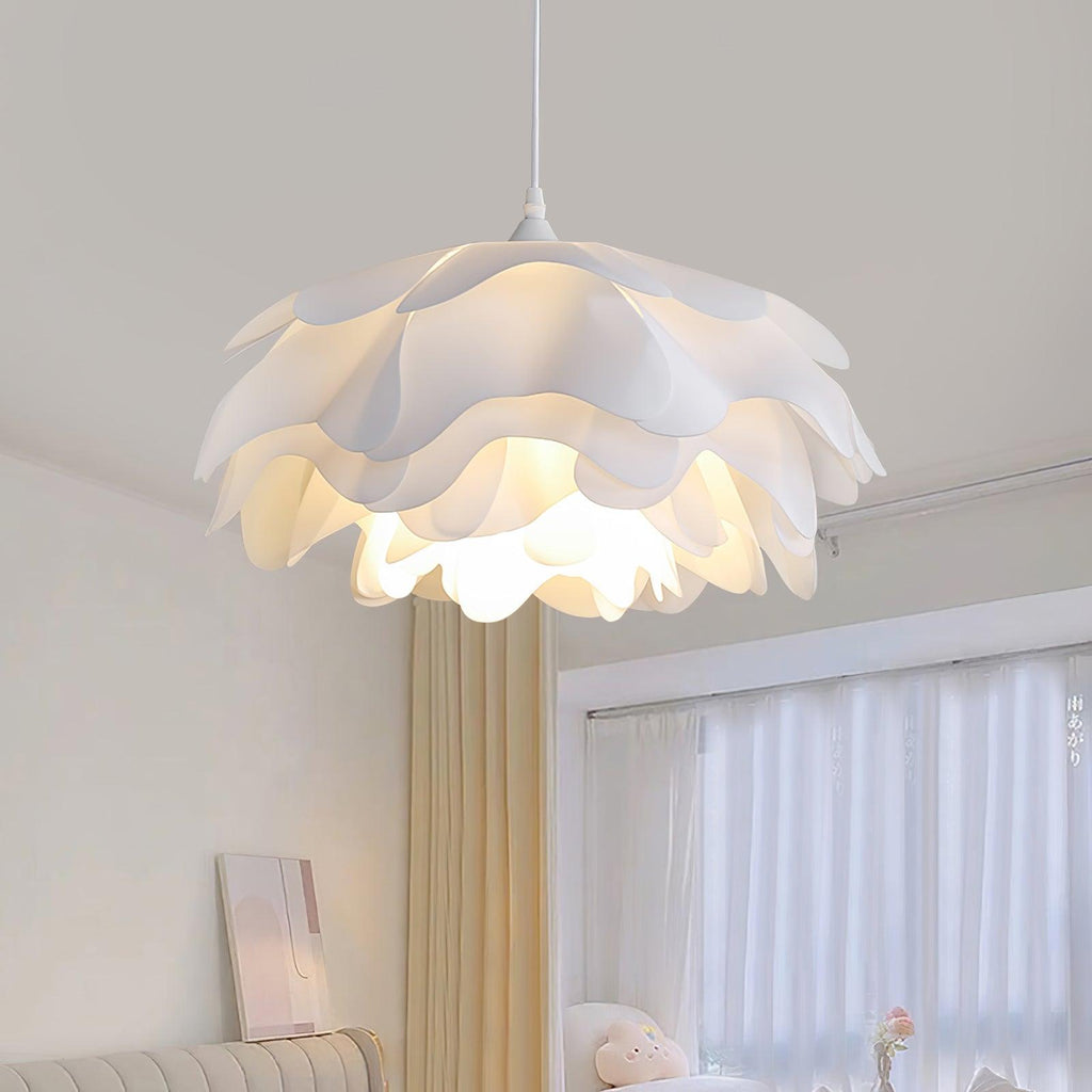 Wide view of the layered petals on this Clérachic pendant, lit from inside, with beige curtains and a bed behind it.