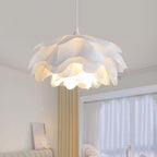 Wide view of the layered petals on this Clérachic pendant, lit from inside, with beige curtains and a bed behind it.