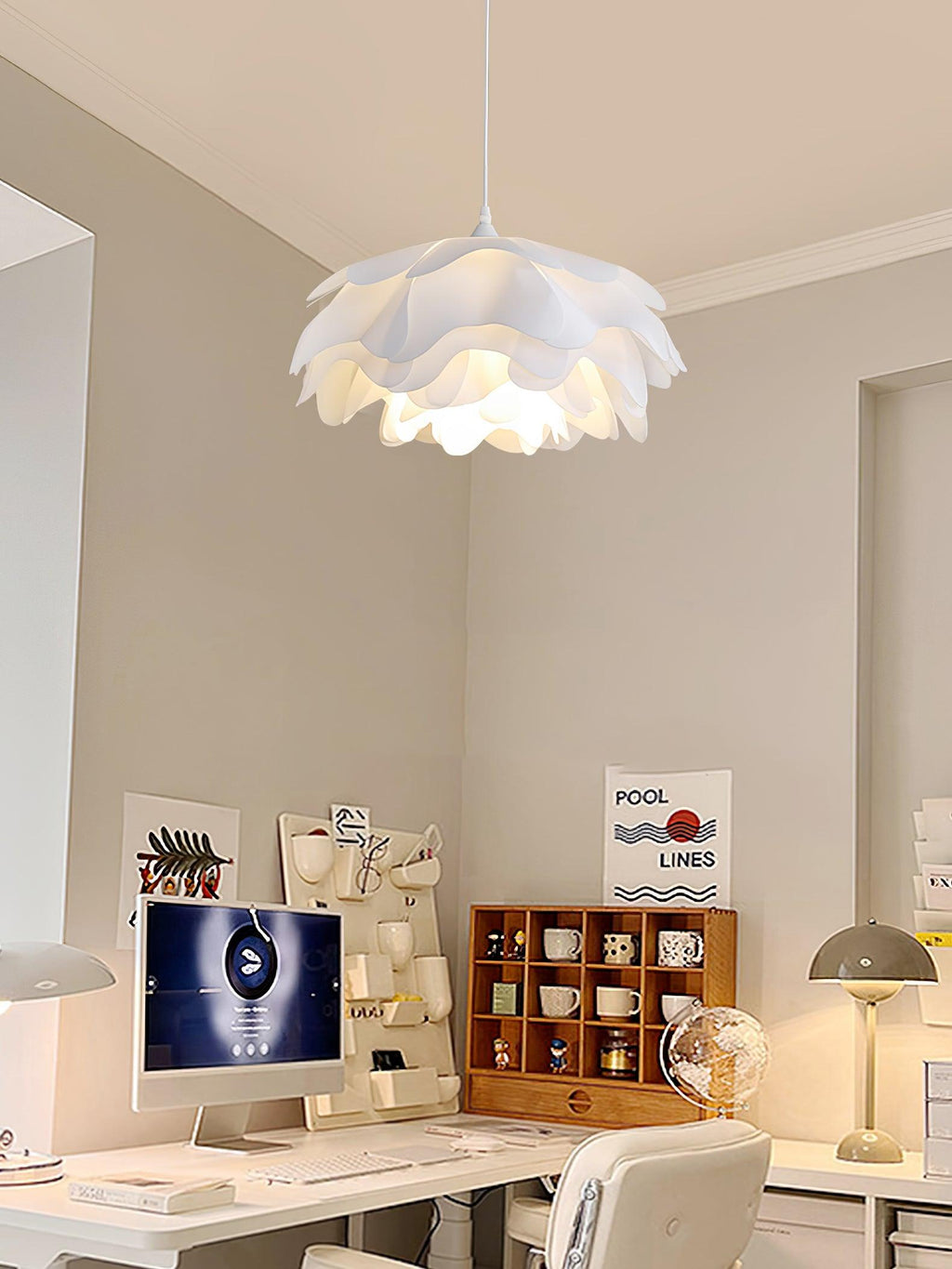 A Clérachic petal pendant above a home-office desk with a monitor, a shelf of mugs and a framed poster on the wall.