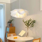Clérachic pendant glowing over a small white table with oranges and a book stand, beside a wooden cabinet and a leafy branch.