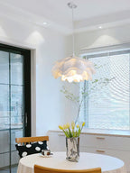 This Clérachic pendant hangs above a white-framed doorway and window with blinds, with tulips in a silver vase on a table below.