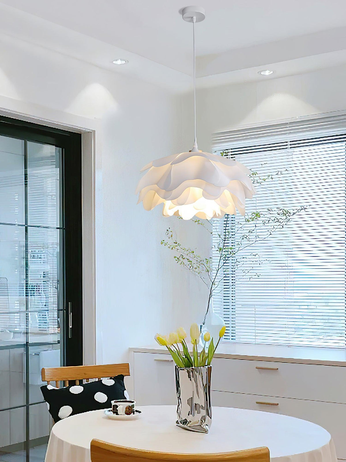 This Clérachic pendant hangs above a white-framed doorway and window with blinds, with tulips in a silver vase on a table below.