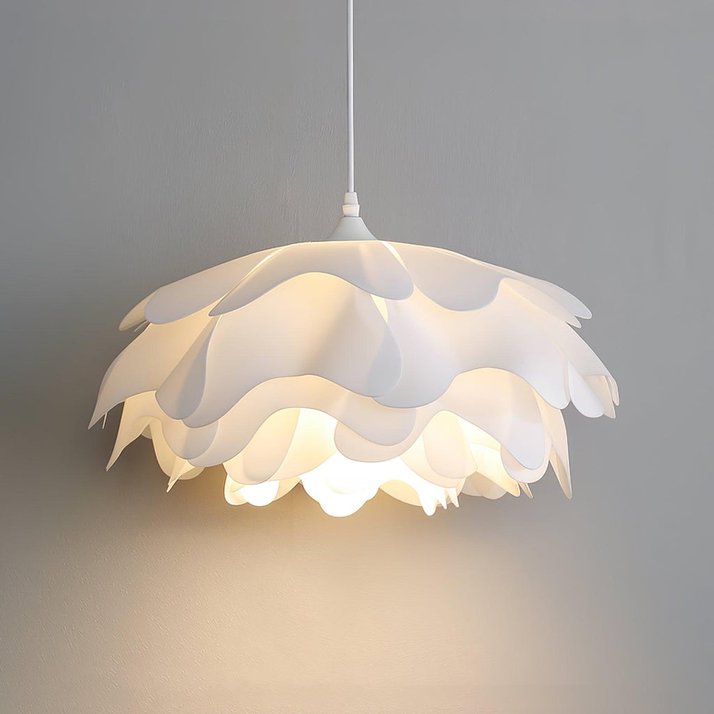 Close view of a lit Clérachic pendant with broad scalloped petals, glowing warmly against a grey wall.