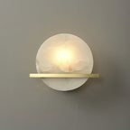 Clérachic White Alabaster Wall Sconce lit on a plain grey wall, the warm centre fading out to cooler white at the disc edges.