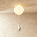 Clérachic ceramic bear reaches upward on its cord, suspended just under a glowing frosted glass ceiling globe.