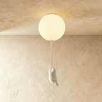 Clérachic flush-mount ceiling light shows a lit frosted glass globe with a white bear figurine dangling below.