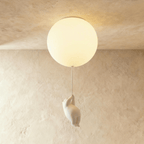 Clérachic bear balloon ceiling light with a single globe glowing warm, figurine suspended against a plaster wall.