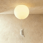 Clérachic single frosted glass globe ceiling light with a bear figurine mid-climb, set on a warm plaster wall.