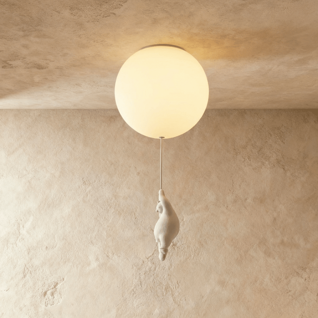 Clérachic flush-mount globe light glows warm with a small bear figurine gripping the cord just below it.