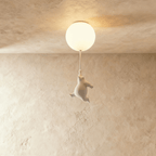Clérachic white bear figurine dangles from a cord under a frosted glass globe on a soft plaster backdrop.