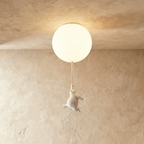 Clérachic bear balloon ceiling light glows above a figurine reaching upward toward the frosted glass globe.