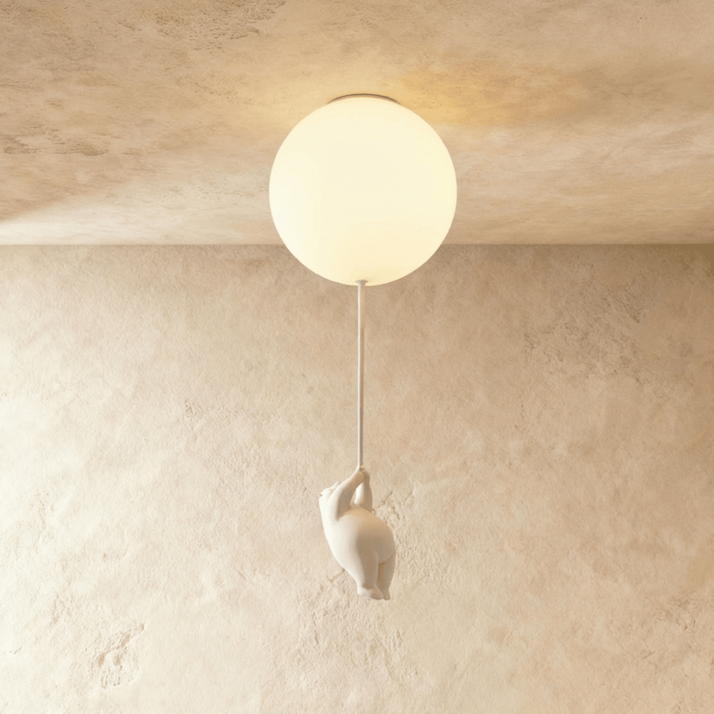 Clérachic single frosted glass globe ceiling light glows warm, a bear figurine climbing the cord beneath it.