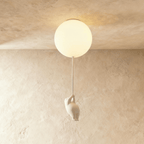 Clérachic single frosted glass globe ceiling light glows warm, a bear figurine climbing the cord beneath it.