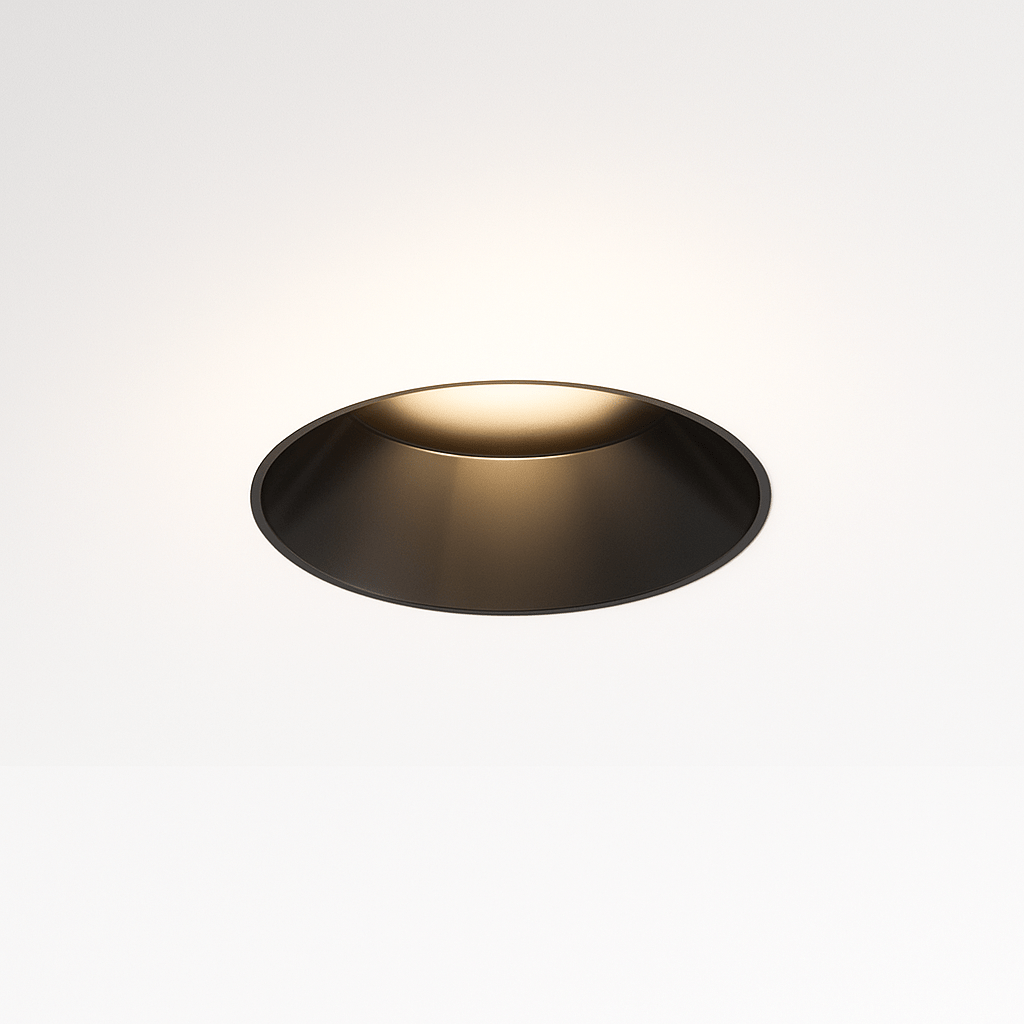 Clérachic trimless downlight glowing warm white from its black cone, the round housing sitting flush against the ceiling.
