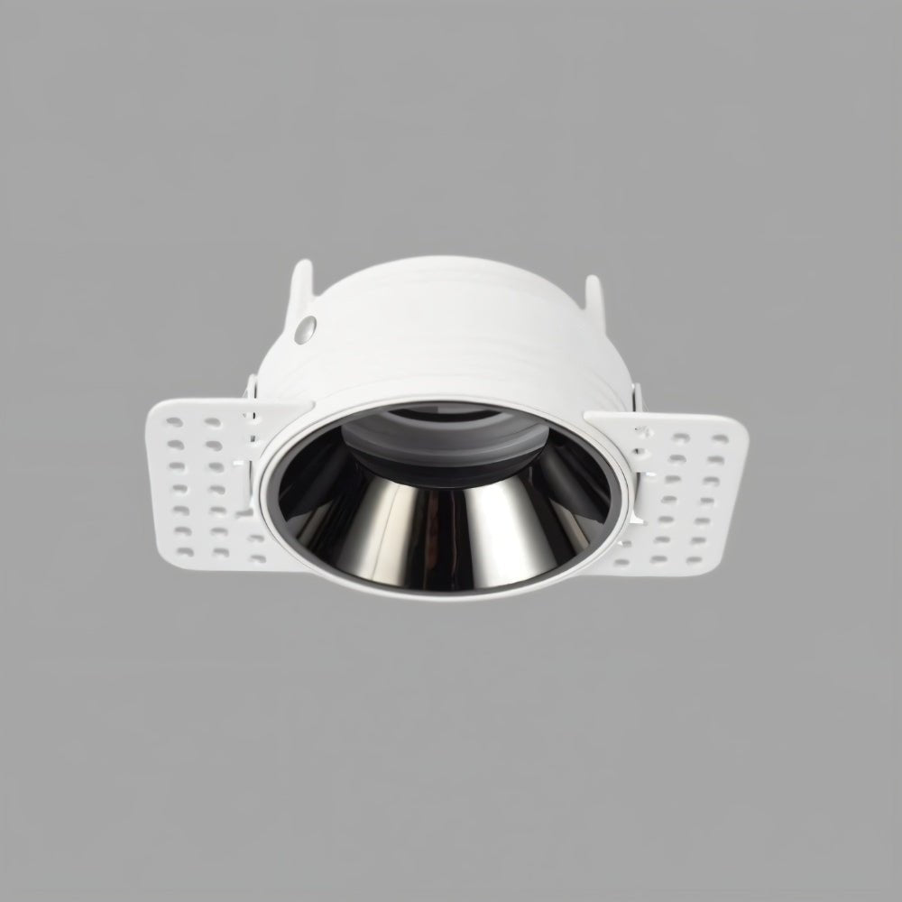 Clérachic trimless downlight housing at an angle, showing the white plaster-in frame and mounting flaps beside the chrome cone.