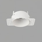 Clérachic trimless downlight shown front-on in white, the smooth cone and plaster-in flanges visible against gray.
