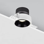 Clérachic trimless downlight installed at a ceiling edge, black cone casting warm light with the heat sink module exposed above.
