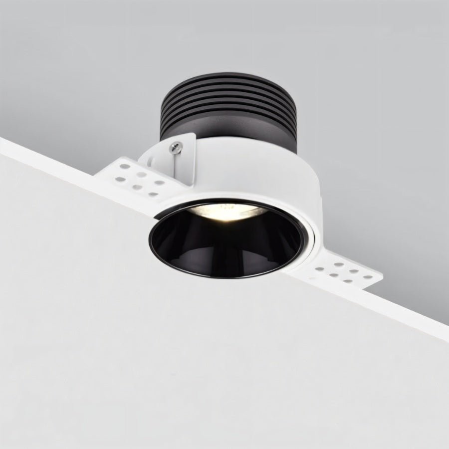 Clérachic trimless downlight installed at a ceiling edge, black cone casting warm light with the heat sink module exposed above.