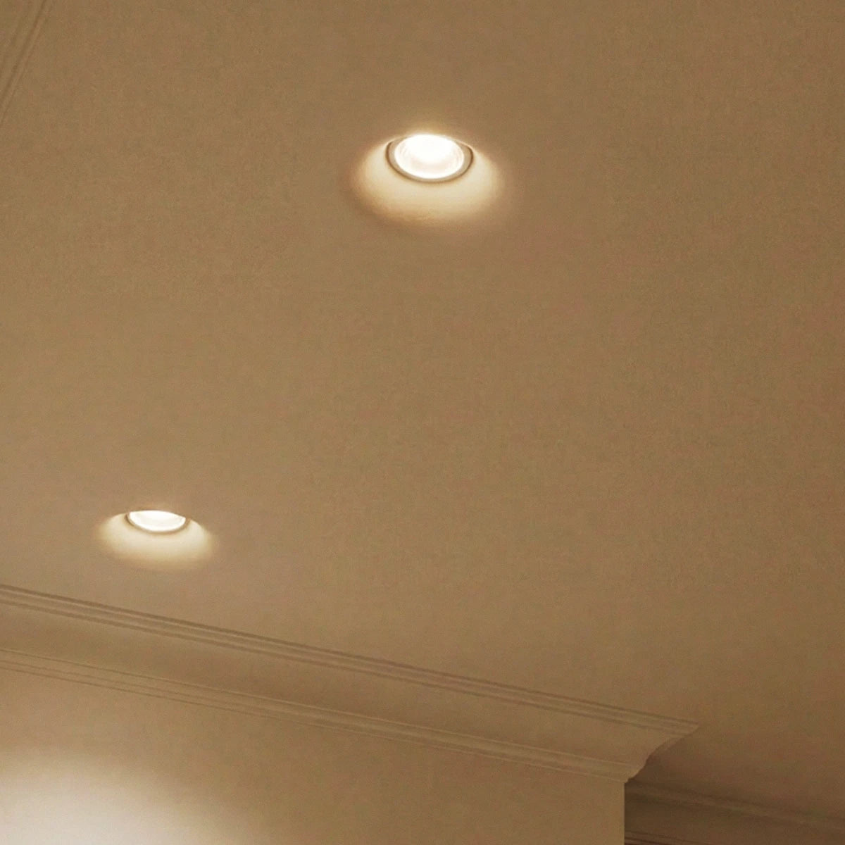 Clérachic trimless recessed downlights in close detail, their flush rings glowing softly against a plaster ceiling.