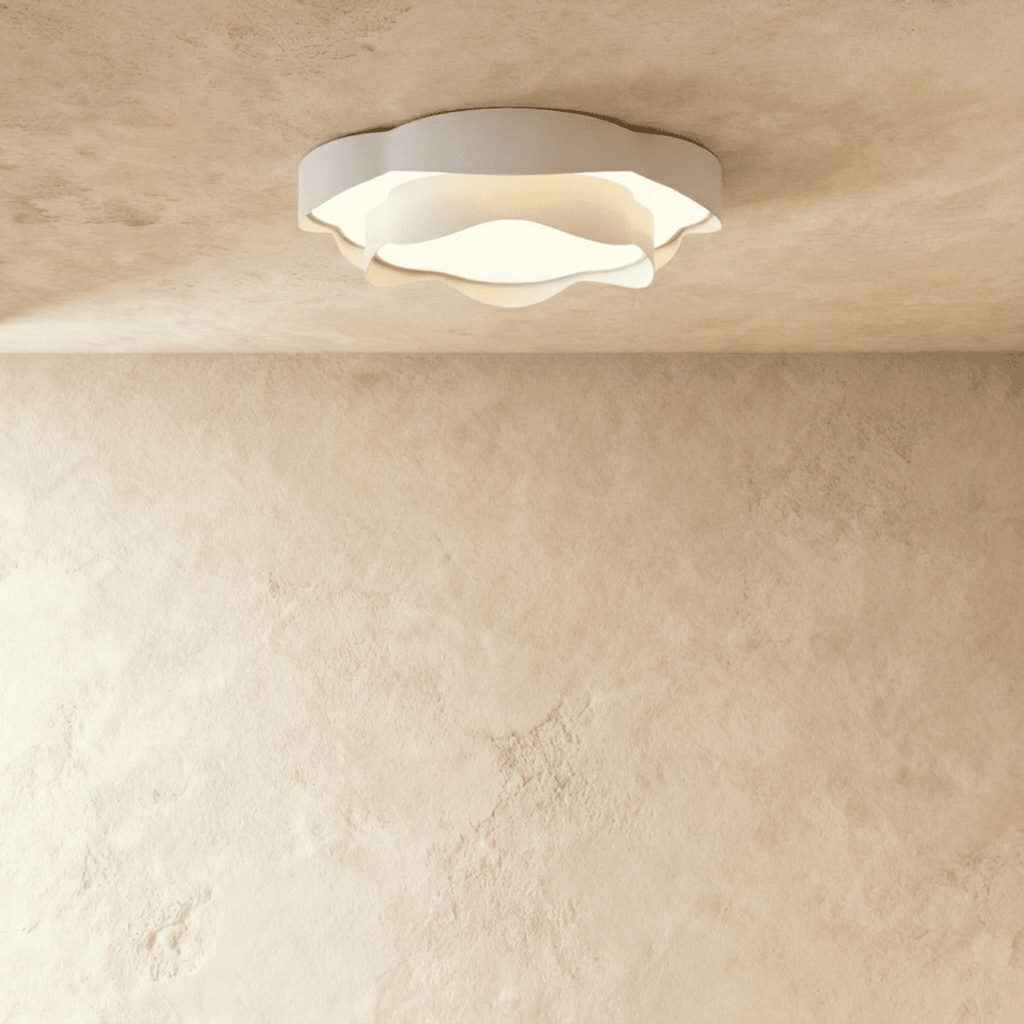Clérachic round white ceiling light with ruffled petal-like edges and a frosted centre, switched on against a limewash backdrop.
