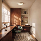 Clérachic white ruffle-edged ceiling light lit above a walnut-panelled study with a green leather chair and a patterned rug.