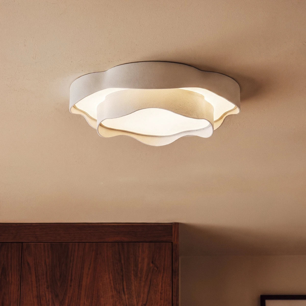 Clérachic close-up of a white layered ceiling light with ruffled edges and a frosted diffuser, above a walnut cabinet.