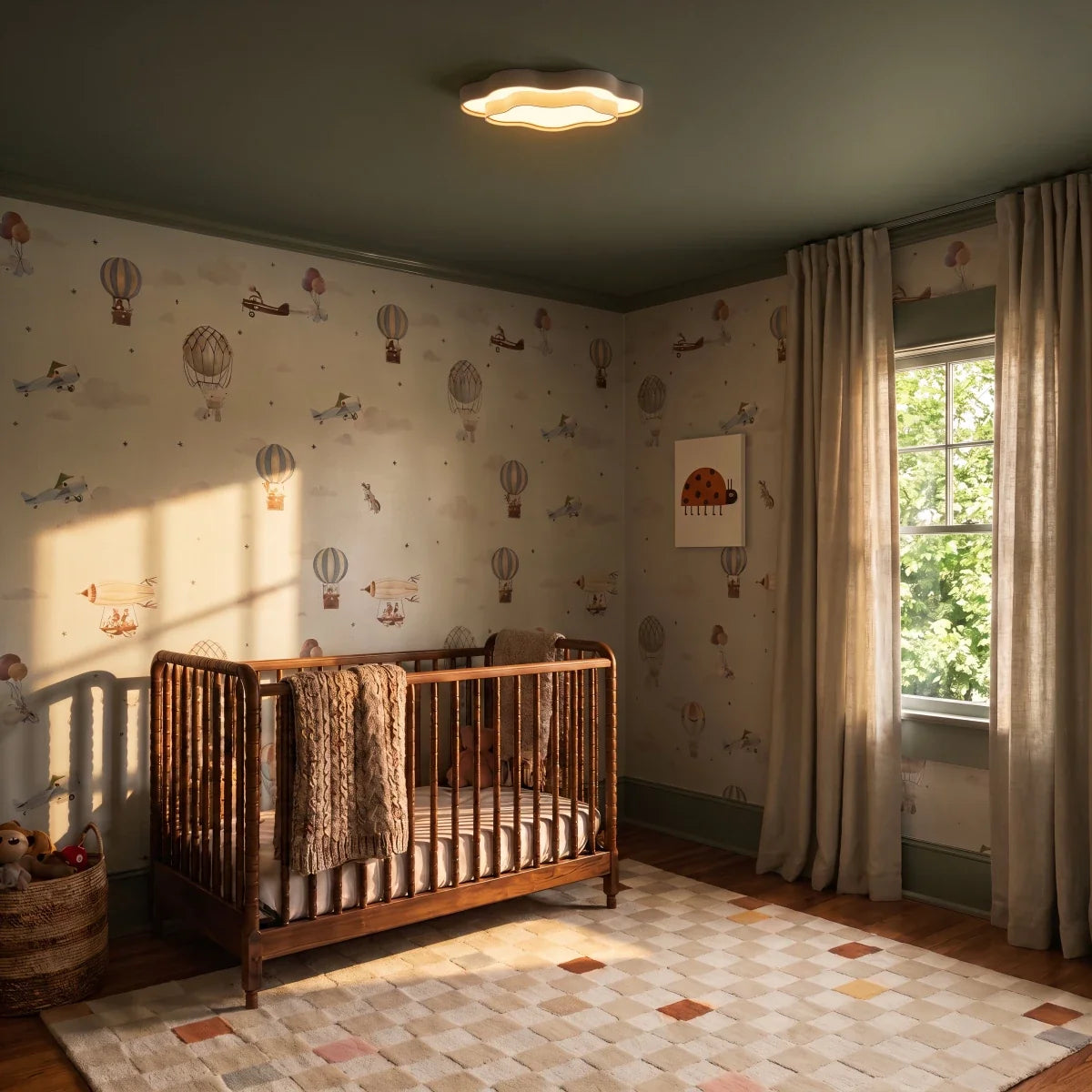 Clérachic cloud-shaped white ceiling light glowing in a nursery with sage ceiling, wooden cot and balloon wallpaper.