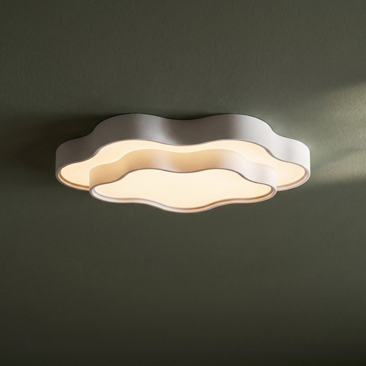 Clérachic white wavy two-tier ceiling light with a lit frosted diffuser, close up on a deep green ceiling.