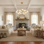 A gold Clérachic ring chandelier with white petals hangs in a room with exposed beams, a stone fireplace and two cream sofas.