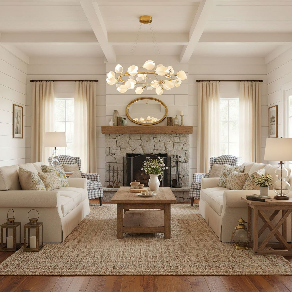 A gold Clérachic ring chandelier with white petals hangs in a room with exposed beams, a stone fireplace and two cream sofas.