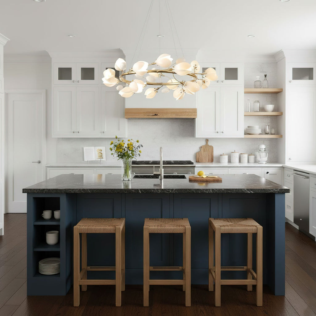 Clérachic ring chandelier with white petal shades above a navy kitchen island with three rattan stools and a white kitchen behind.