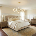 Clérachic petal chandelier in a gold ring, hanging above a cream upholstered bed with side tables and table lamps in a pale yellow room.