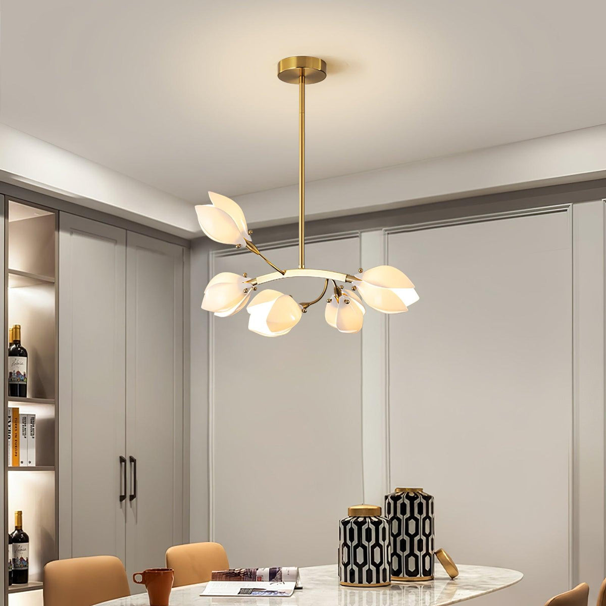 Clérachic white petal chandelier on a gold rod in a dining room, with a pale cabinet wall and a table with patterned vases.