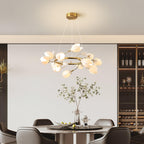 Clérachic ring chandelier with white petals on fine cables, above a round dining table with dark chairs and a wine rack at the back.
