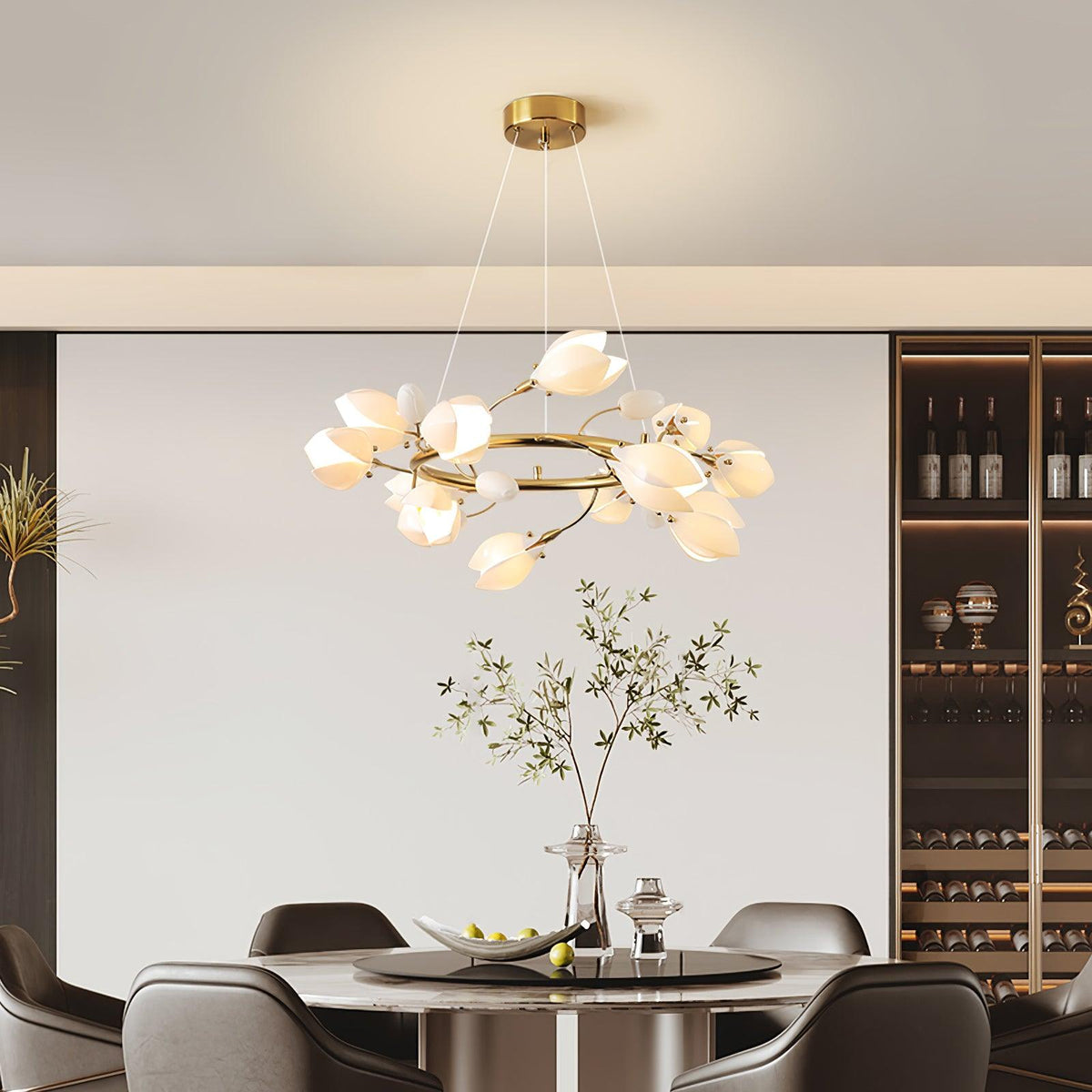 Clérachic ring chandelier with white petals on fine cables, above a round dining table with dark chairs and a wine rack at the back.