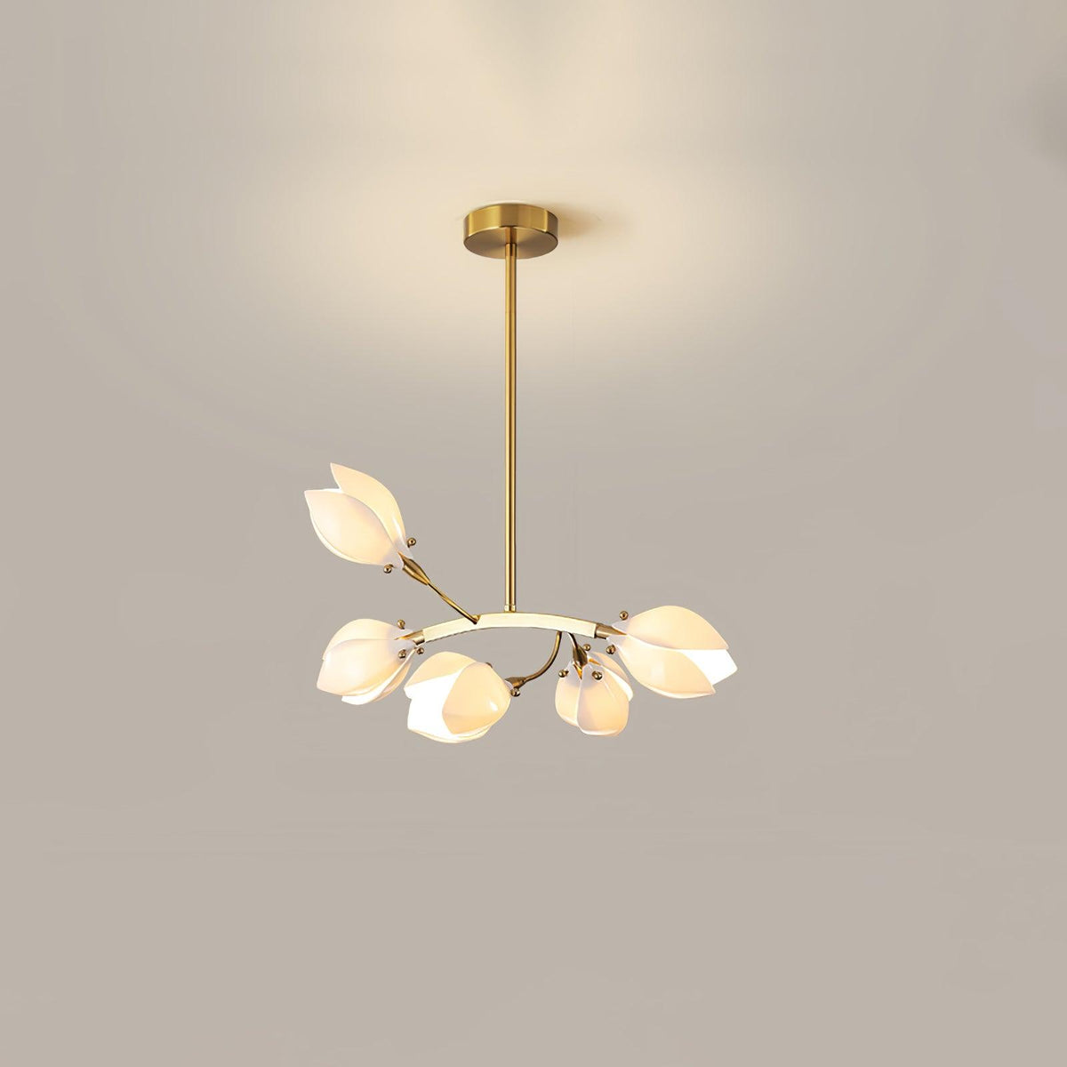Clérachic chandelier with a gold stem and a curved arm of white petal shades, lit against a plain beige wall.
