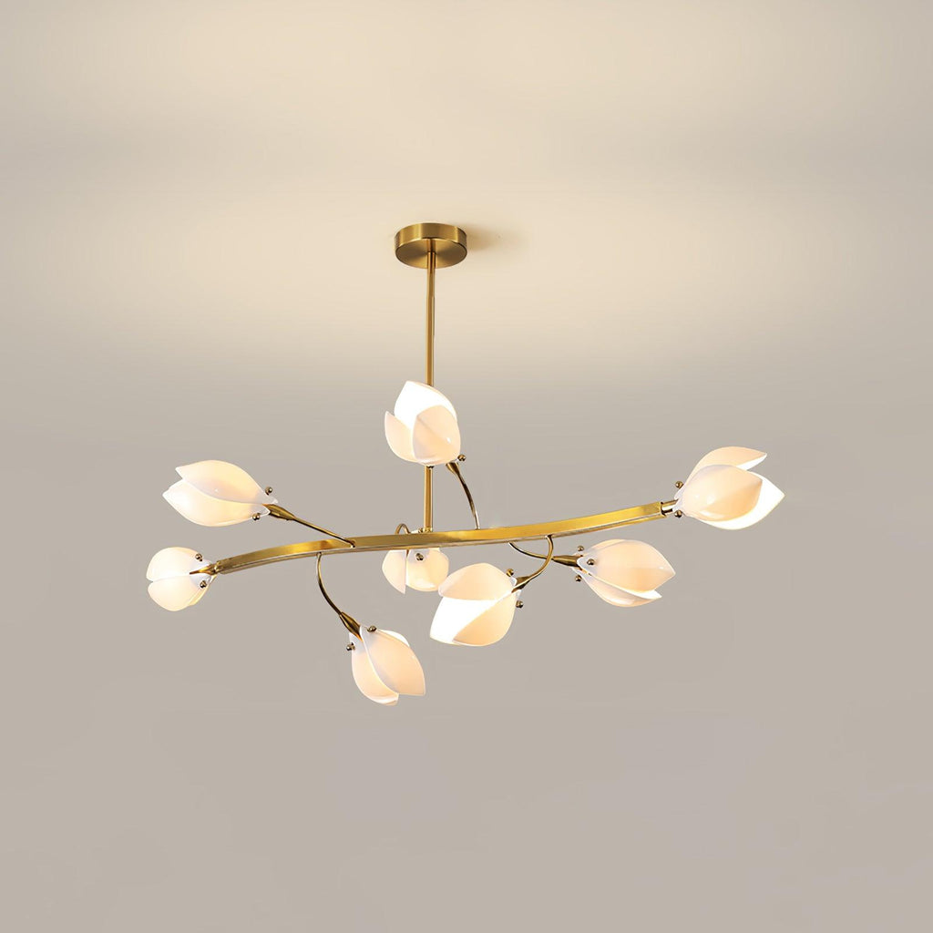 Clérachic chandelier with a gold rod, a long curved arm and white petal shades, lit against a plain beige wall.