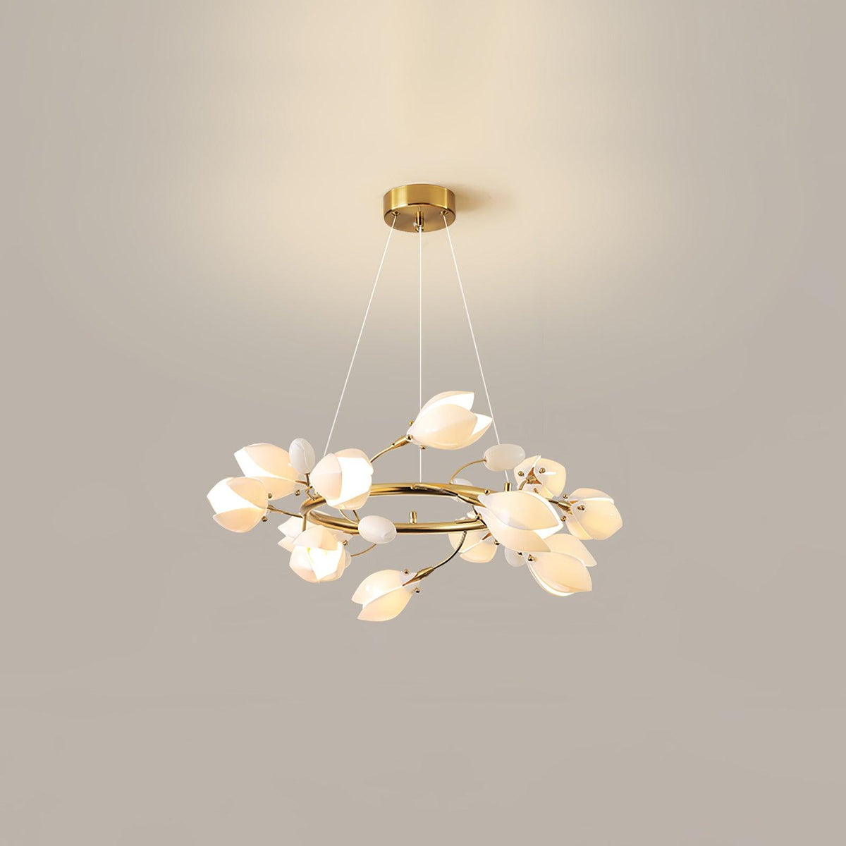 Clérachic ring chandelier lit against a beige wall, hanging on three fine cables from a round gold canopy, with white petal shades.