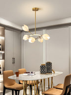 Clérachic petal chandelier on a gold rod above a marble-topped oval dining table with tan chairs and gold legs.