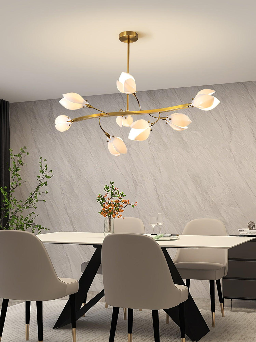Clérachic chandelier with a long gold arm and white petals above a pale dining table and taupe chairs, against a grey stone-effect wall.