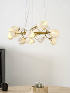 Closer view of a lit Clérachic chandelier with its white ceramic petals in a cluster, above a stone table and a candle holder.