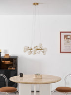 Clérachic ring chandelier on a gold canopy and cables, over a round stone table, with a black display cabinet and a framed print.