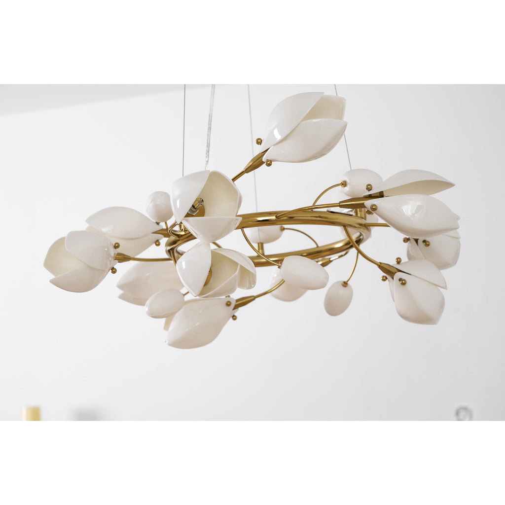 Side view of a Clérachic chandelier with gold coiled branches, white ceramic petals and small buds, on a white backdrop.