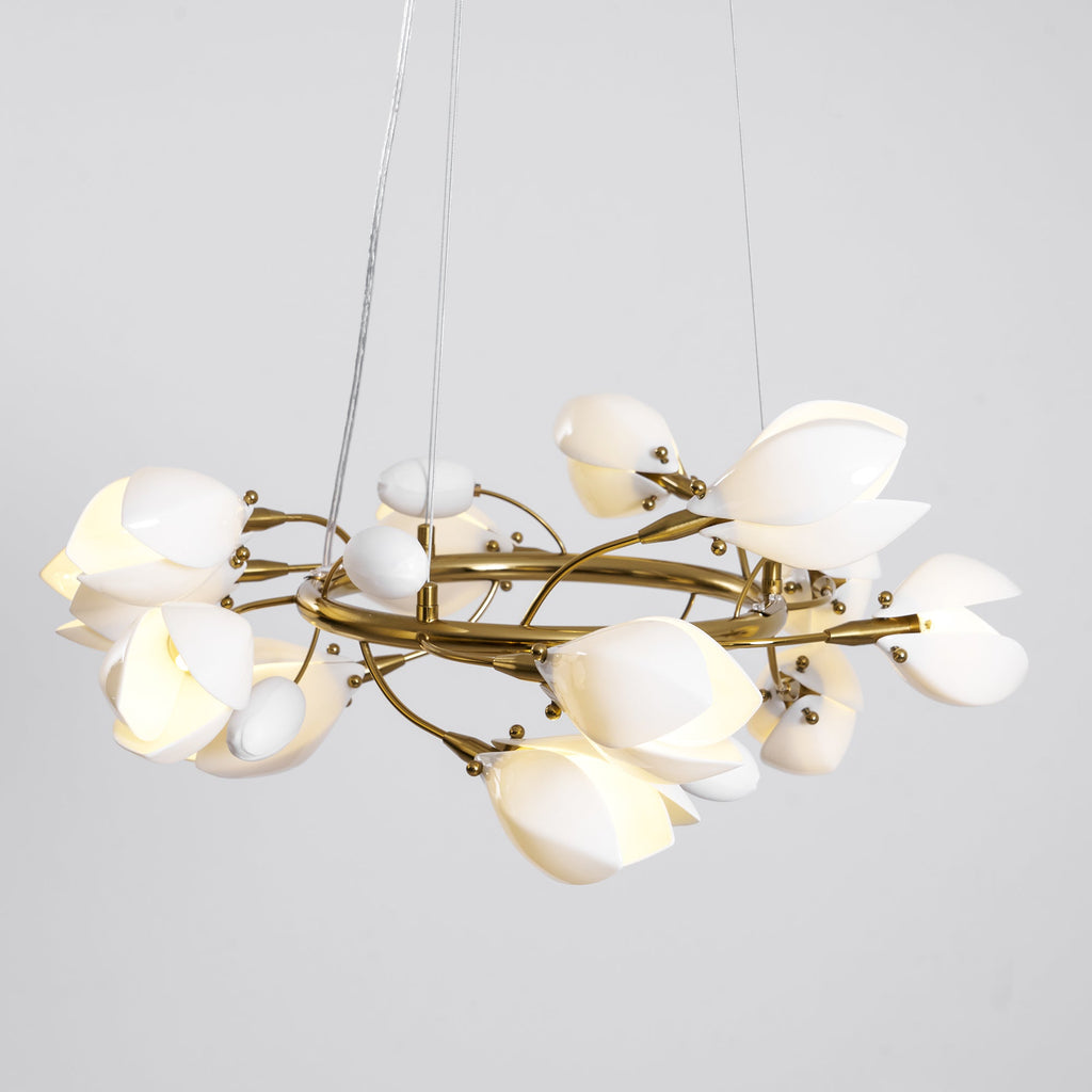 Clérachic chandelier lit on a grey backdrop, hung from two thin cables, with white petals and egg-shaped buds on a gold ring.